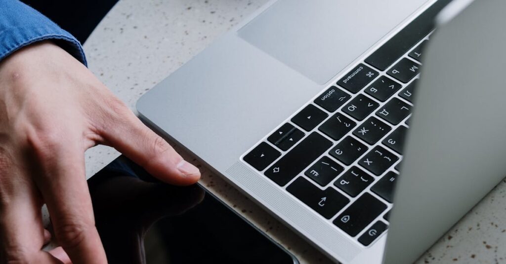A close-up of hands exchanging phone next to a laptop on a round table.